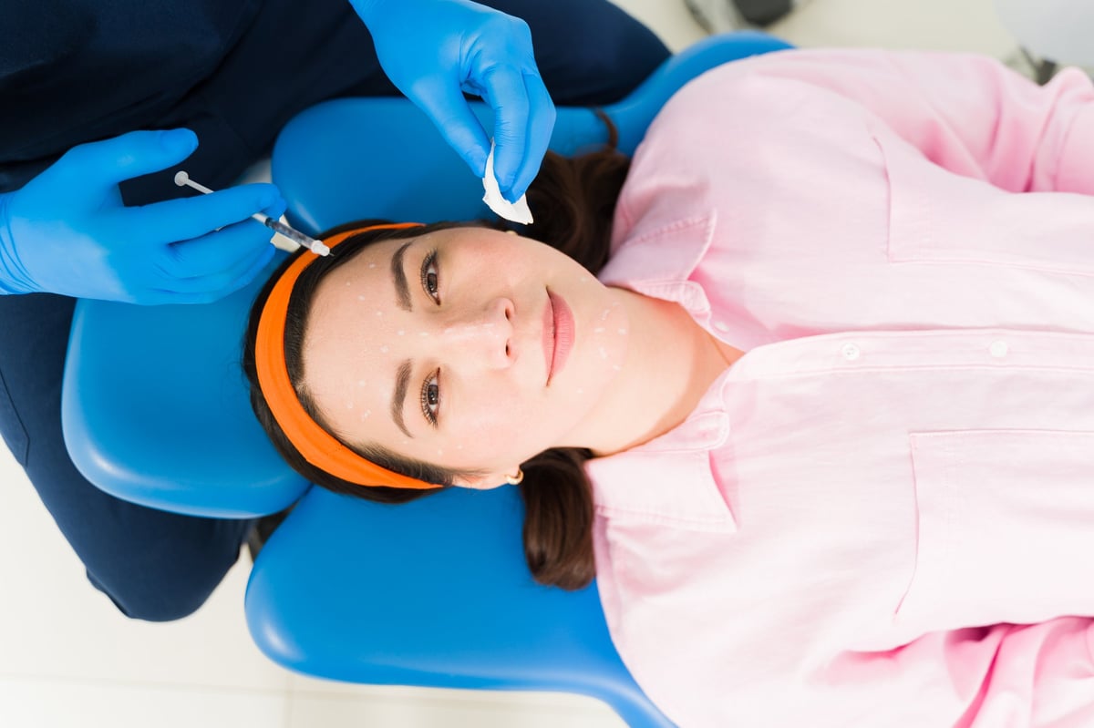 Beautiful woman receiving hyaluronic acid skin booster injections for deep hydration and glowing skin