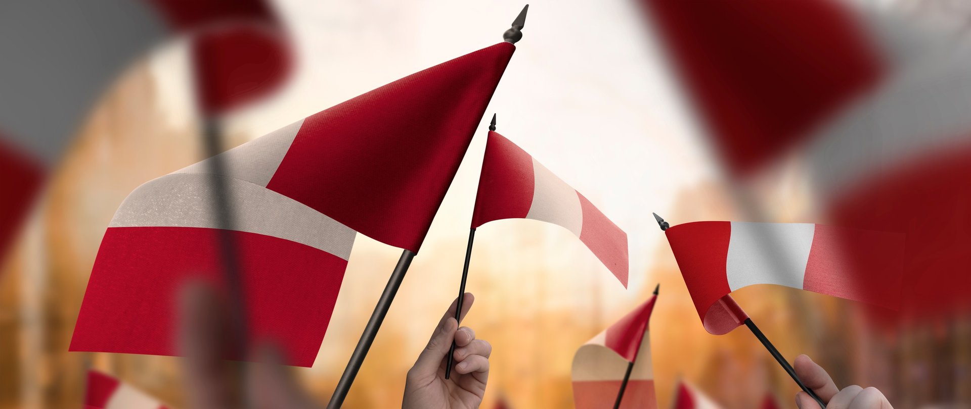 Peru flags in their hands on a blurred urban background. Fiestas Patrias celebration.