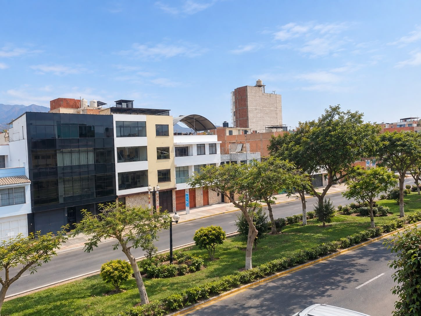 Urban street view with colorful modern apartment buildings, trees, and pedestrian pathway on a sunny day