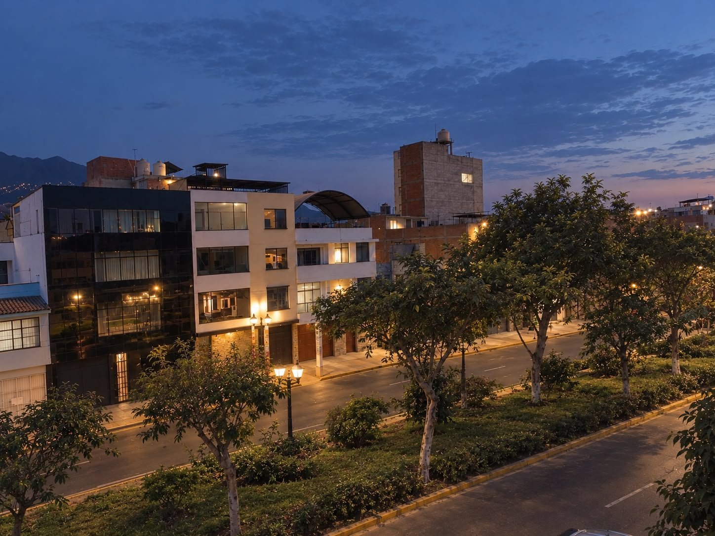 Modern residential buildings illuminated at dusk with trees and streets in an urban neighborhood at twilight